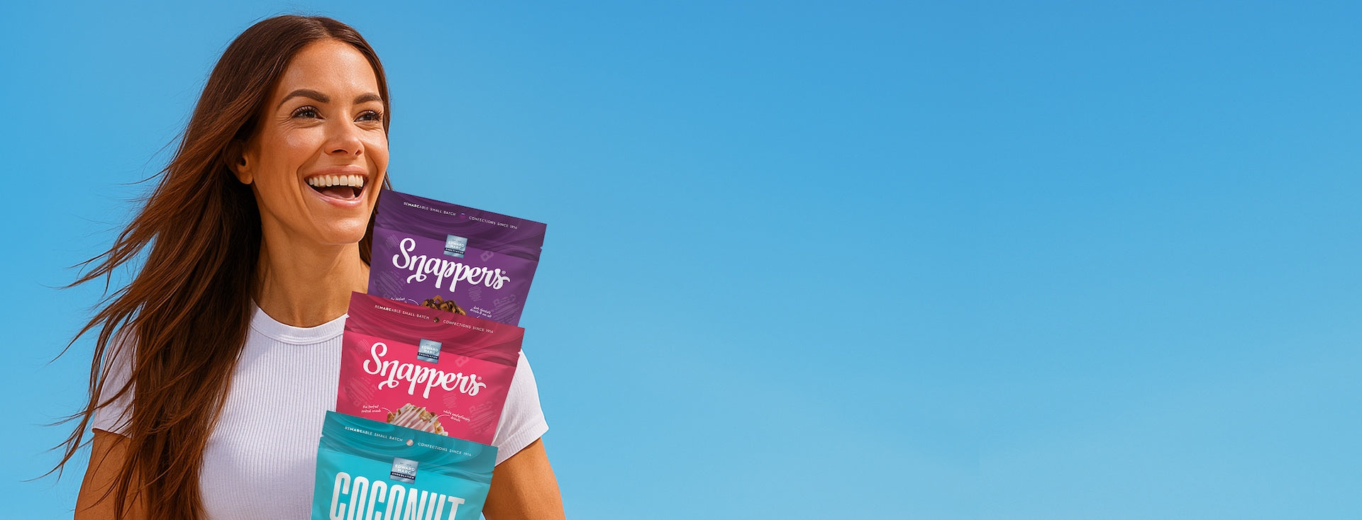 Woman holding Snepers coconut products against a blue background